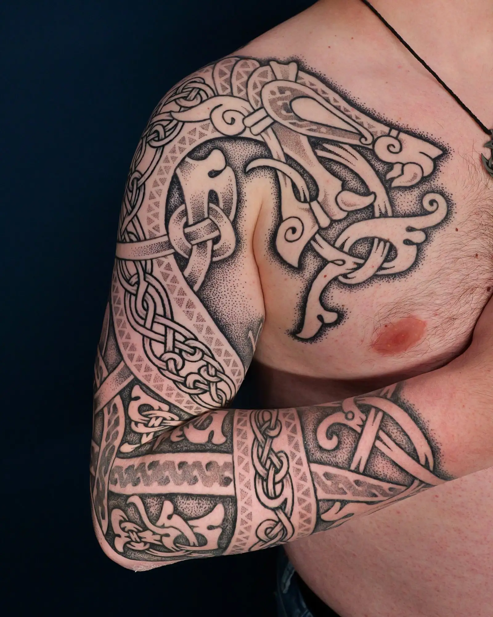 Detailliertes nordisches Tattoo im Dotwork-Stil, das sich über Schulter, Brust und Arm eines Mannes erstreckt.