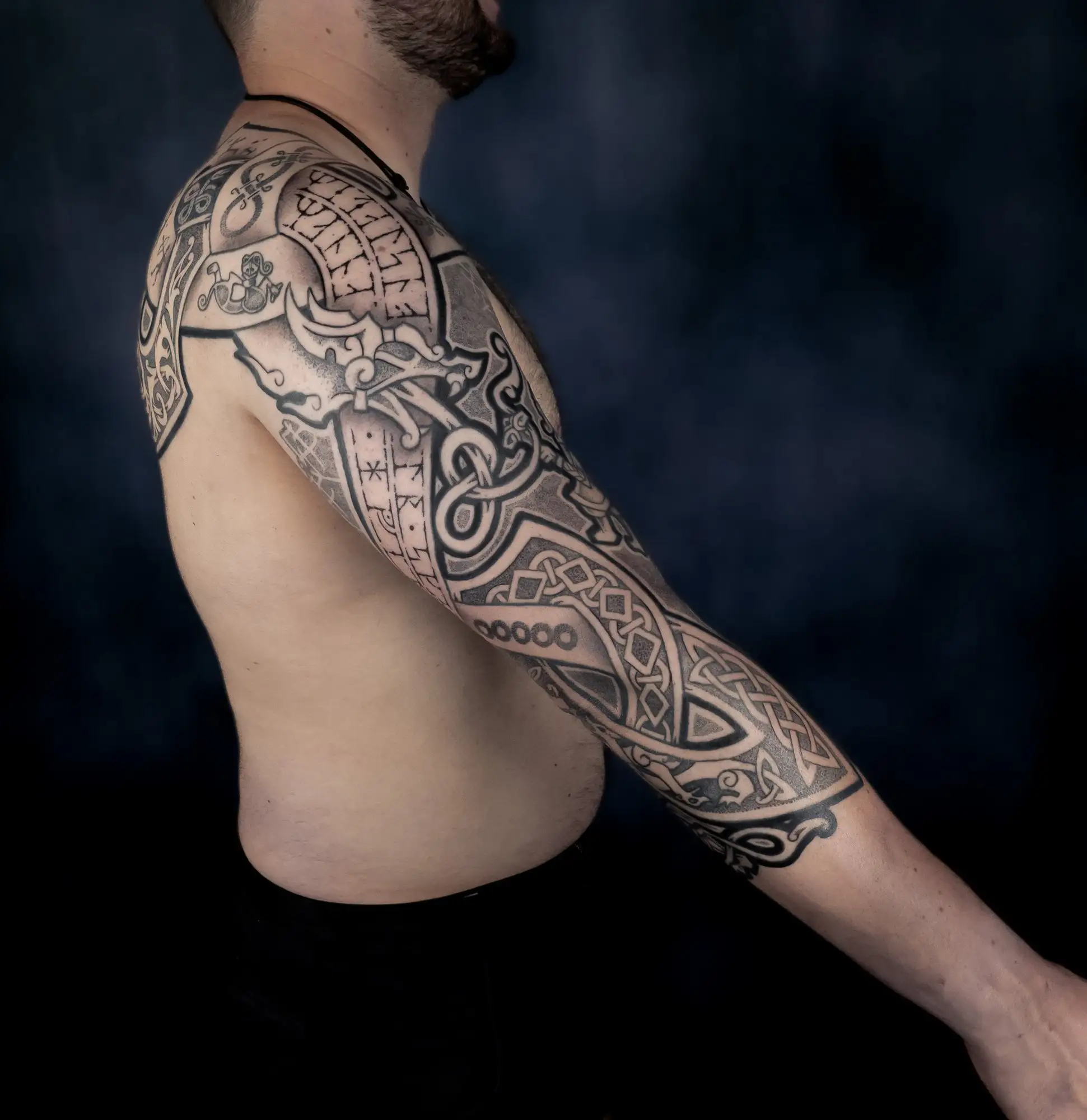 Männlicher Arm mit einem komplexen, detaillierten nordischen Drachen- und Knoten-Tattoo-Sleeve.